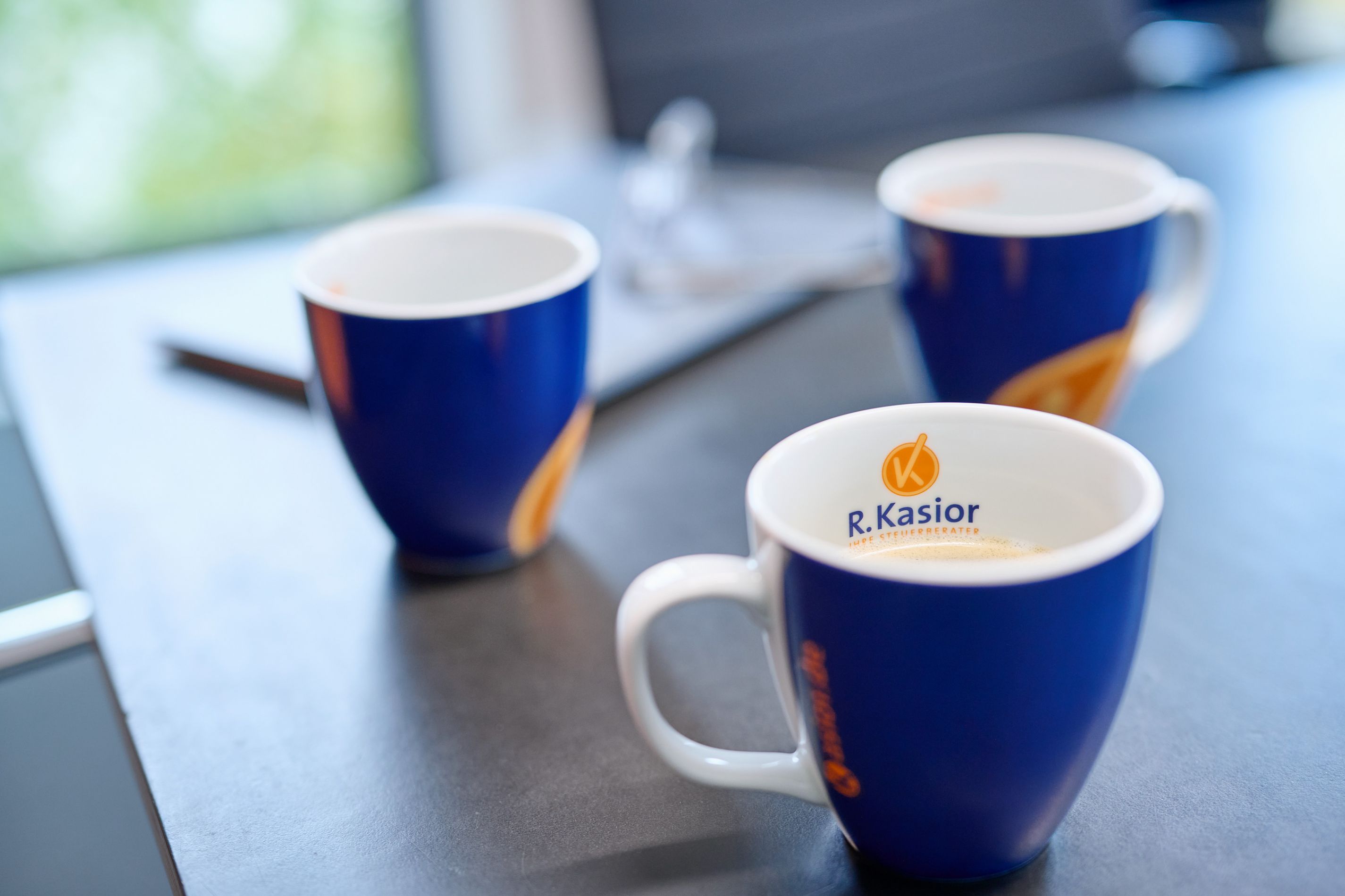 Tassen mit dem Logo der Steuerberater Kasior auf einem Konferenztisch